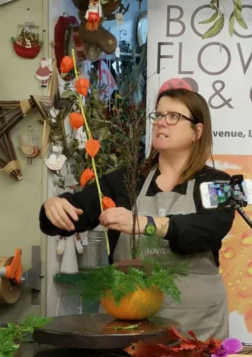 Fleur from Booker flowers demonstrating how to make an autumnal flower arrangment on a seasonal flower class